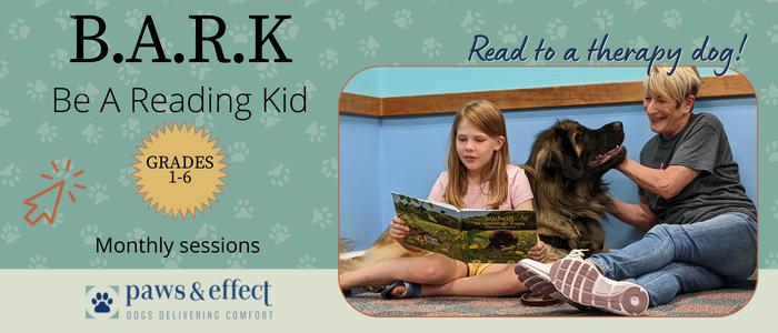Young girl reading to a therapy dog and her handler for the BARK: Be a reading kid program.